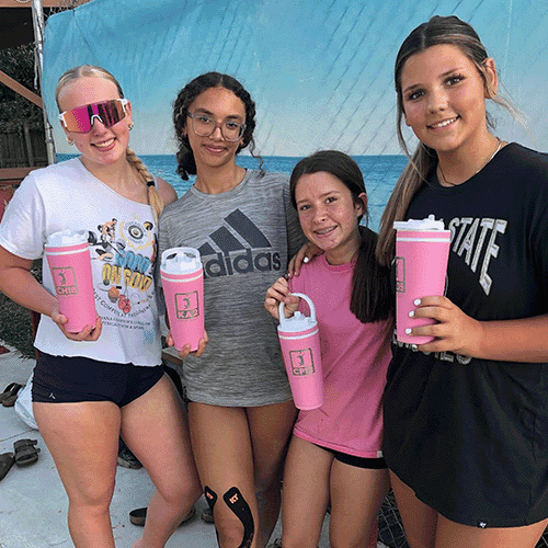 Four teammates on the beach with their logo bottles